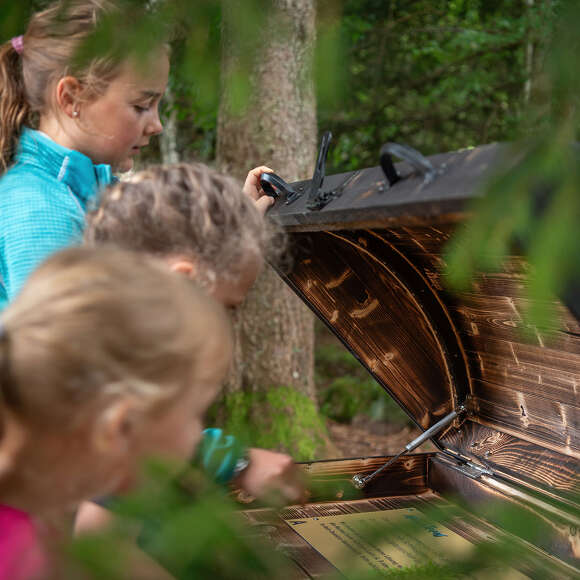 Kinder an einer Schatztruhen-Station auf dem MounTeens Detektivweg am Imberg in Steibis