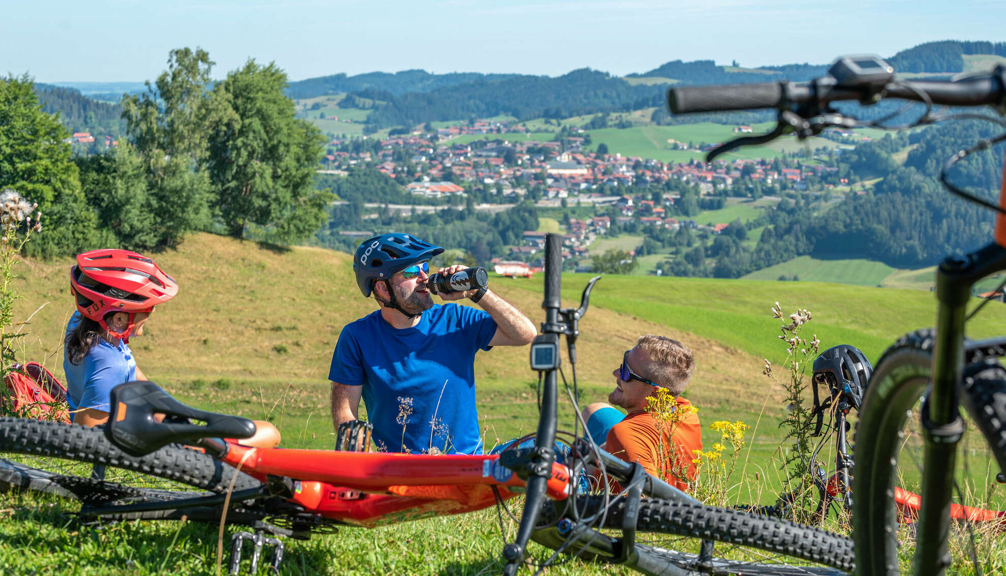 Radgruppe liegt in der Wiese und macht eine Pause beim Radeln in Oberstaufen.