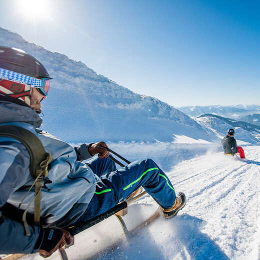 Rodeln auf der Naturrodelbahn am Hochgrat mit Bergpanorama der Allgäuer Alpen.