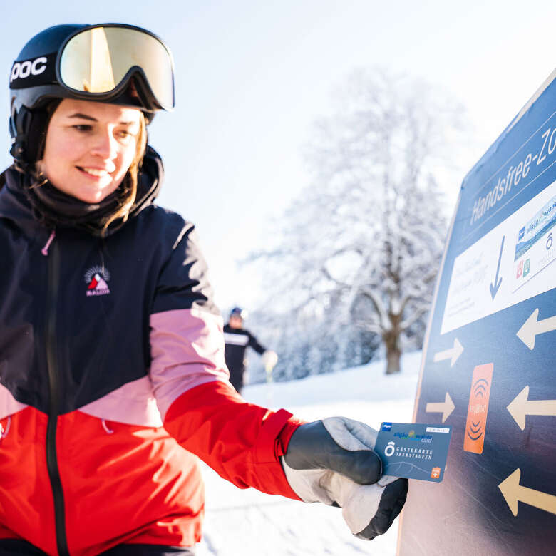 Skifahrerin mit der Oberstaufen PLUS Karte am Drehkreuz beim Skifahren in Oberstaufen