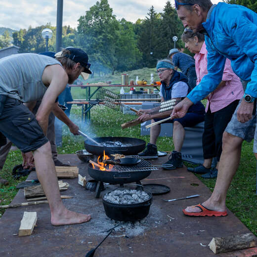 Gruppe lernt wie man Lagerfeuer macht und auf dem Feuer kocht