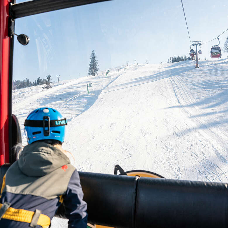 Auffahrt mit der Hündlebahn mit Blick auf die Piste an einem sonnigen Wintertag in Oberstaufen.