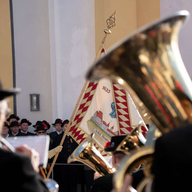 Fahnenschwingen mit Altfähnrichen und Blasmusik auf dem Kirchplatz am Fasnatziestag in Oberstaufen.