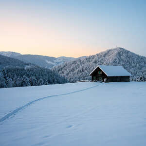 Winterlandschaft am Hompessen mit Bergpanorama und Hütte in der aufgehenden Sonne