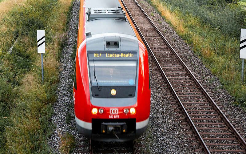 Zug auf der Linie nach Lindau durch die grüne Natur von Oberstaufen mit Bergpanorama