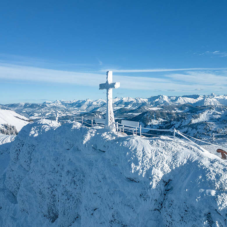 Verschneiter Hochgrat Gipfel mit vereistem Gipfelkreuz und dem Panorama der Allgäuer Berge