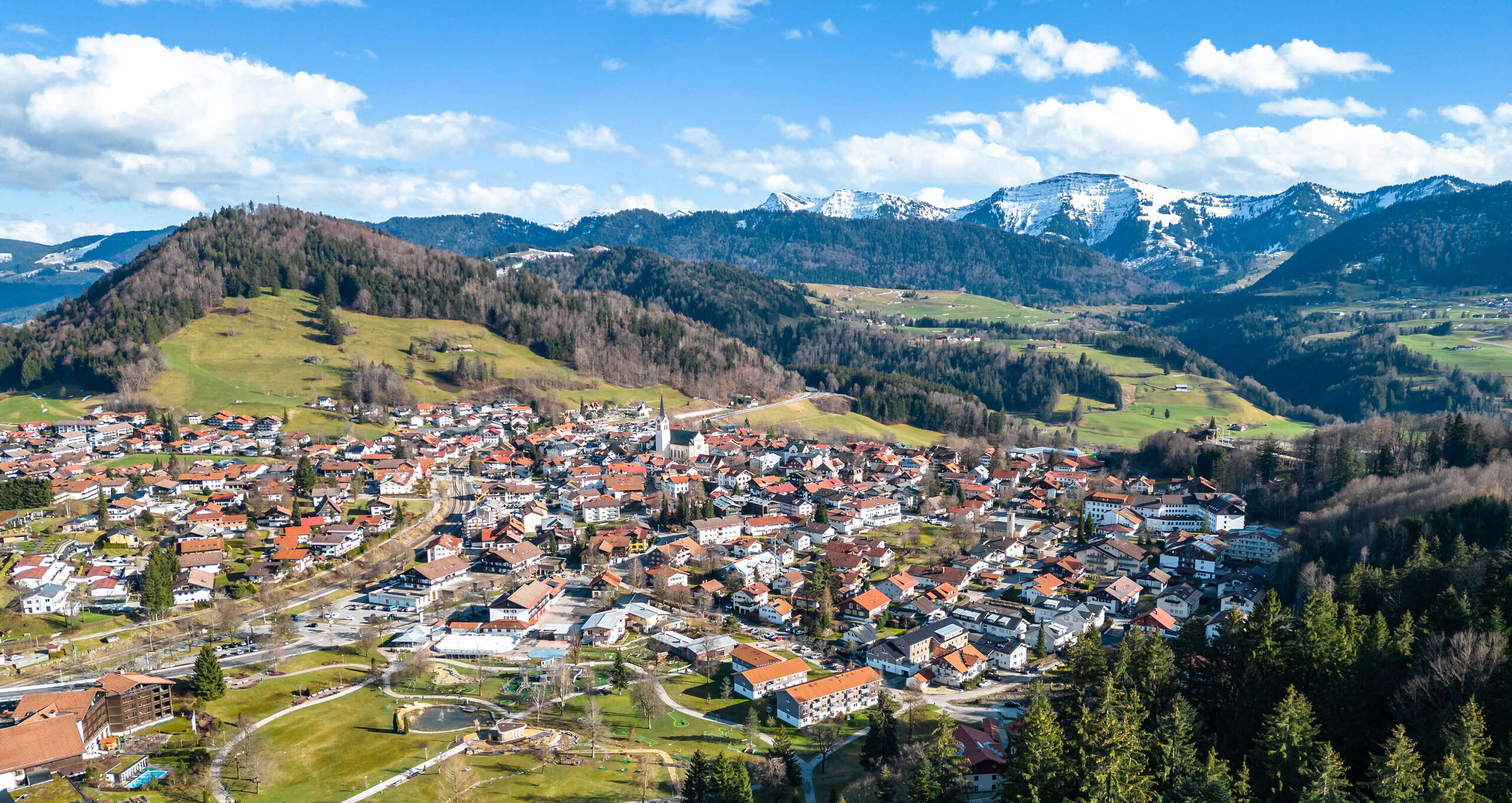 Ortspanorama von Oberstaufen mit dem schneebedeckten Bergen im Frühling