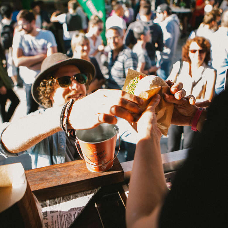 Mann bekommt einen amerikanischen Burger aus einem Street-Food-Wagen gereicht