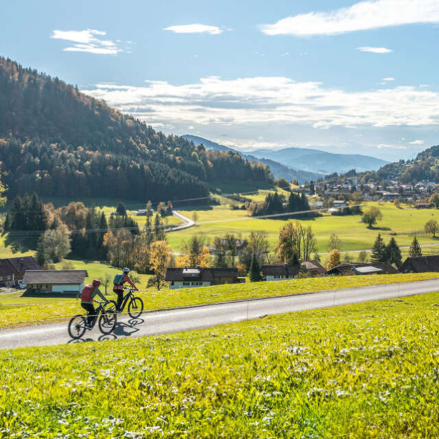 Radfahren am Hompessenweg mit Ausblick auf den Ort und die Berge um Oberstaufen