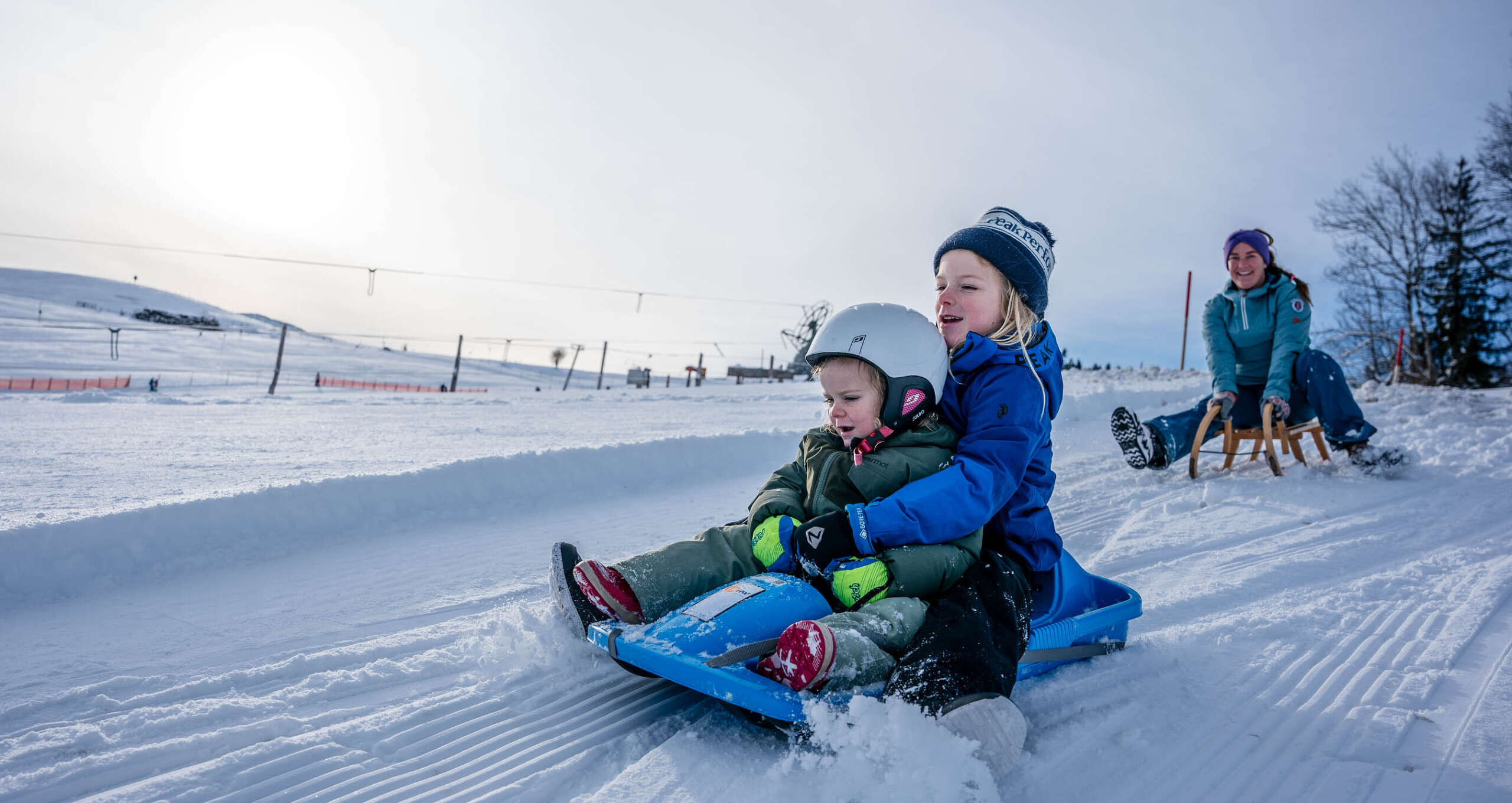 Familie beim Rodeln auf den verschneiten Abfahrten in Oberstaufen