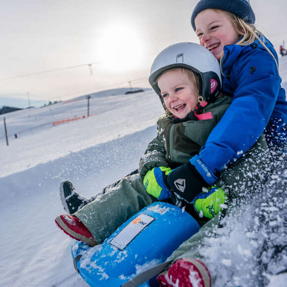 Kinder beim Rodeln im Schnee in Oberstaufen