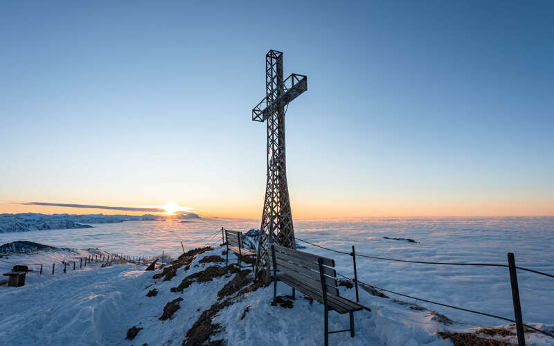 Gipfelkreuz am Hochgrat bei Sonnenuntergang im Winter über den Wolken