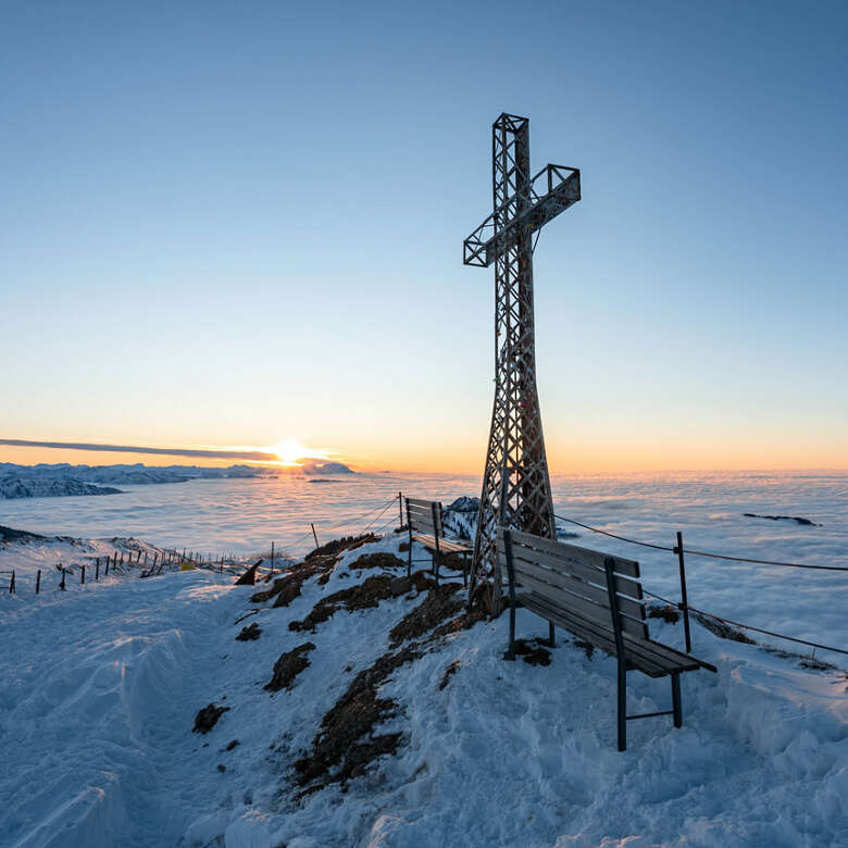 Gipfelkreuz am Hochgrat bei Sonnenuntergang im Winter über den Wolken