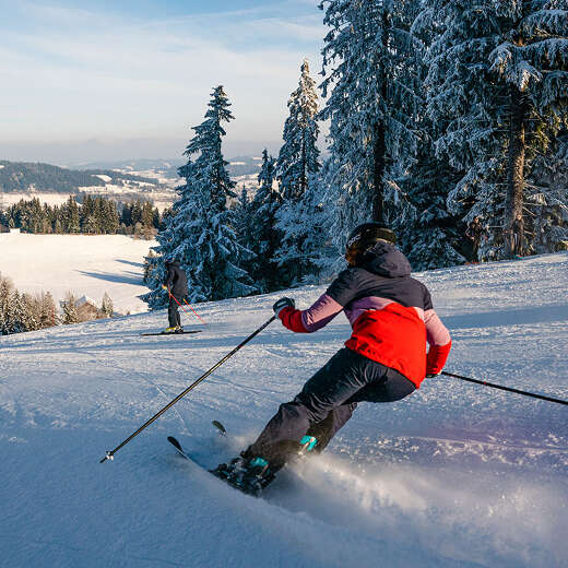 Skifahren auf der Talabfahrt der Skiarena Steibis mit Weitblick auf Oberstaufen