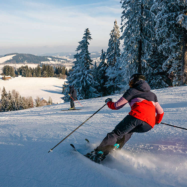 Skifahren auf der Talabfahrt der Skiarena Steibis mit Weitblick auf Oberstaufen