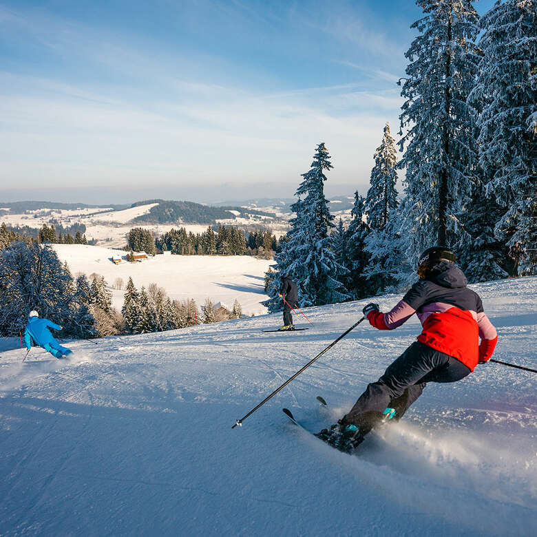 Skifahren auf der Talabfahrt der Skiarena Steibis mit Weitblick auf Oberstaufen