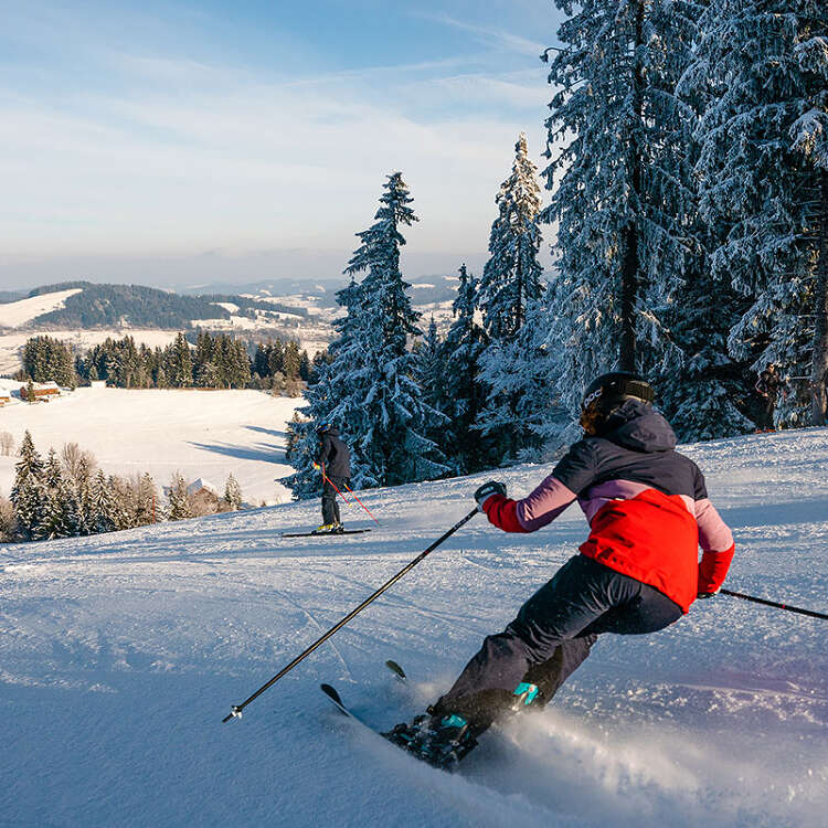 Skifahren auf der Talabfahrt der Skiarena Steibis mit Weitblick auf Oberstaufen