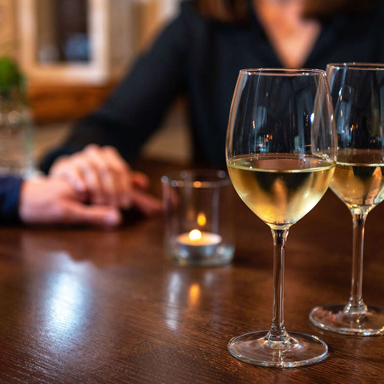 Paar genießt händchenhaltend ein Glas Weißwein