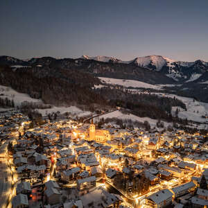 Beleuchtetes Oberstaufen mit Bergpanorama am Abend im Winter