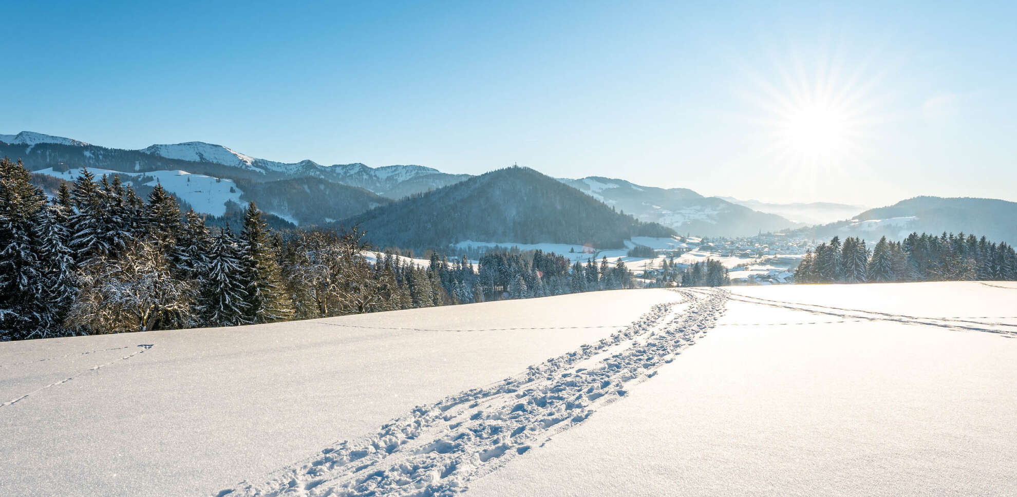 Spuren von Schneeschuhen in verschneiter Natur mit Ausblick auf den Staufen und Berge von Oberstaufen