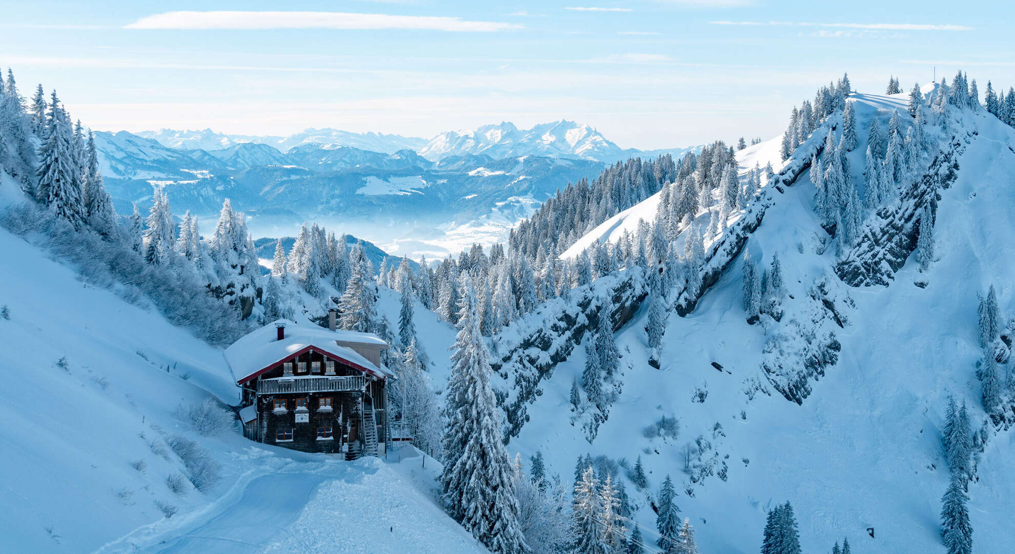 Das Staufner Haus in den verschneiten Bergen mit Panorama der Allgäuer Alpen.