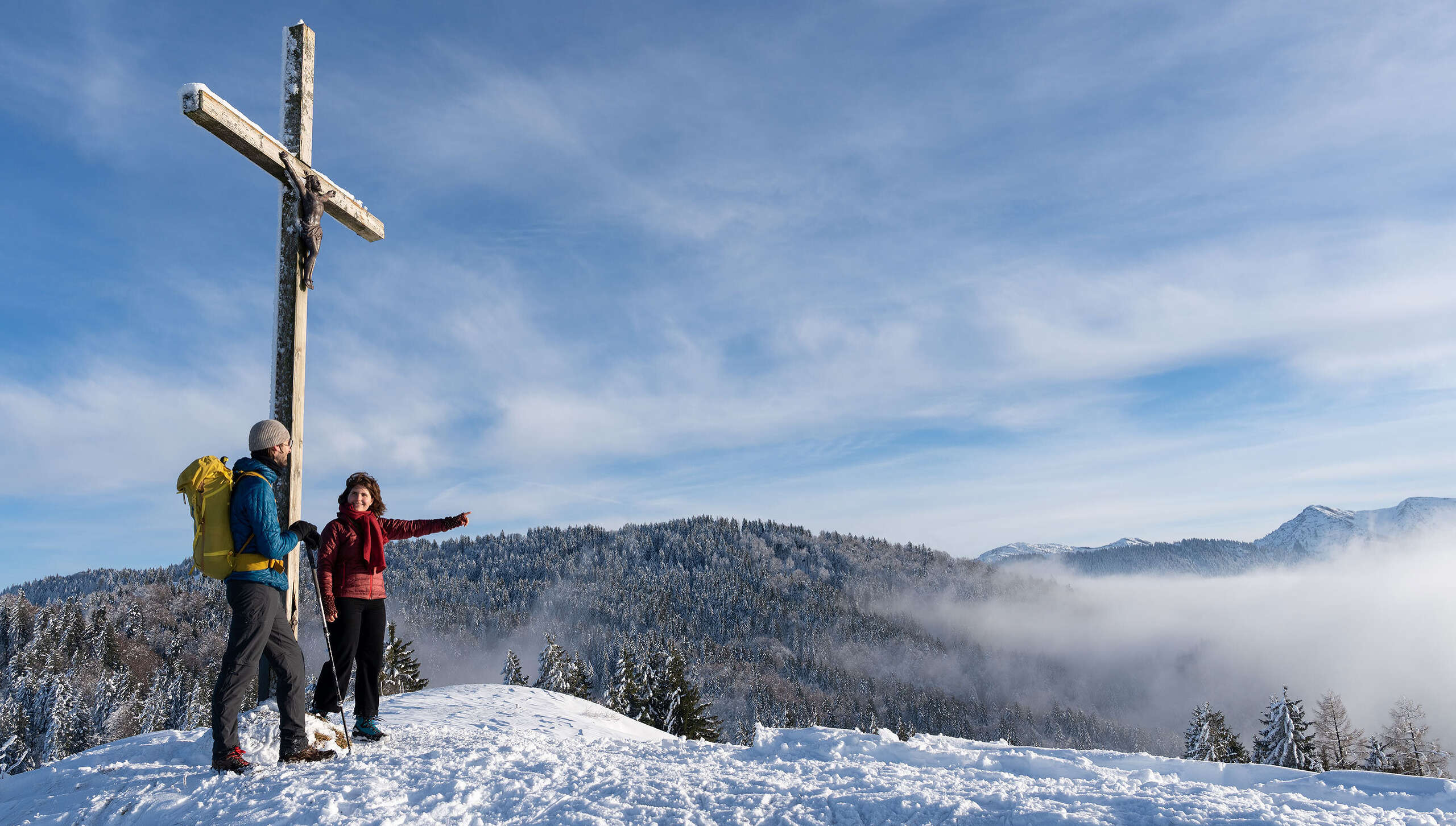 Wanderer am verschneiten Gipfel der Juget-Höhe bei Oberstaufen mit Bergpanorama