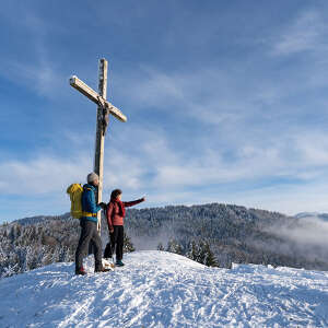 Wanderer am verschneiten Gipfel der Juget-Höhe bei Oberstaufen mit Bergpanorama