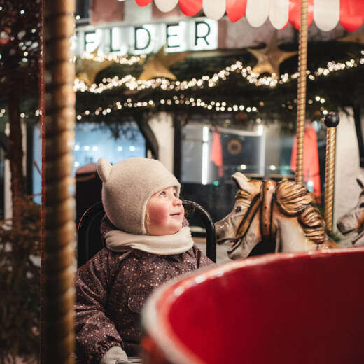 Kind auf dem nostalgischen Karussell während des Oberstaufener Winterzaubers.